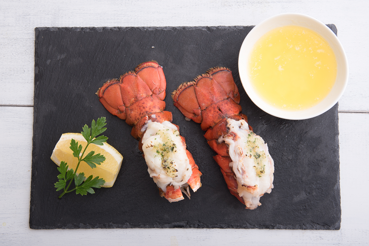 Cooked lobster tails on a plate with butter